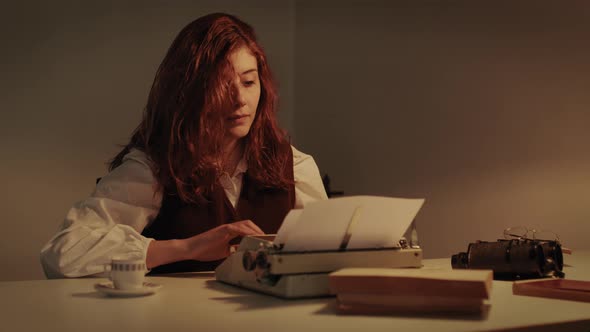 Young Girl Writes on Typewriter at a Table