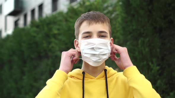 Young man teenager takes off a protective medical blue mask and laughs 