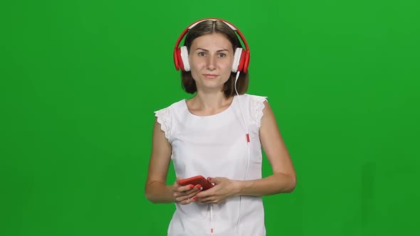 Portrait Young Woman in Big Red Headphones Walking and Listening To Music Vie Mobile Phone on