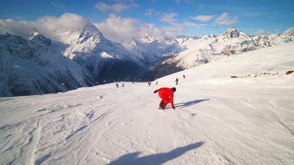 A Snowboarder in an Orange Ski Suit Rolls at High Speed and Falls on the Track
