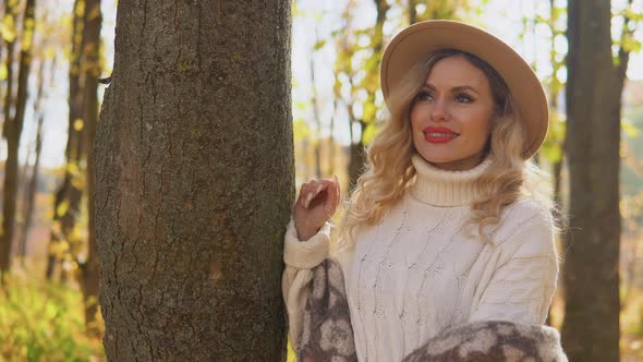 Portrait of a Smiling Happy Cheerful Woman in a Brown Hat in Autumn Park
