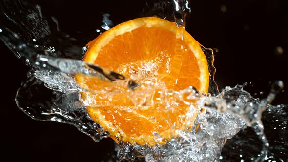 Super Slow Motion Shot of Rotating Fresh Orange Slice and Splashing Water at 1000Fps