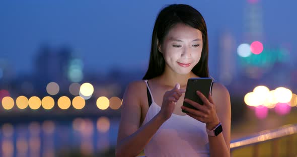 Young Woman use of mobile phone in city at night