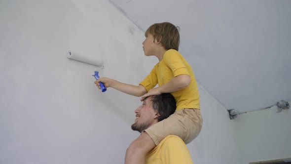 A Father and Son Both Wearing a Yellow Tshirt Paint the Wall Using a Roller Painter