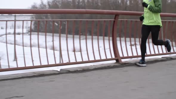 Young Man Jogging on Bridge in Winter