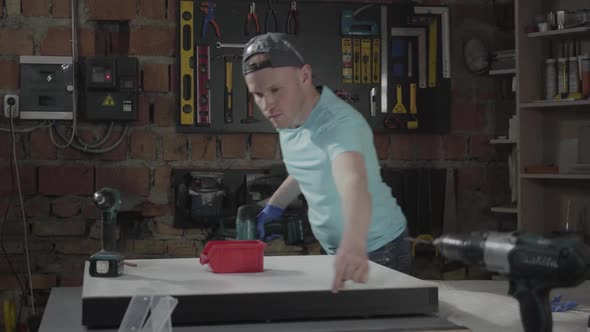 Portrait Craftsman Engineer Focused on Drilling a Hole with Tool on the Background of a Small