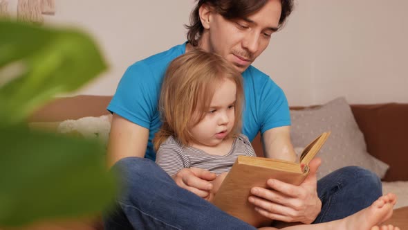 Dad and Daughter Read Book on Bed in Bedroom Process of Learning and Upbringing Little Girl Child