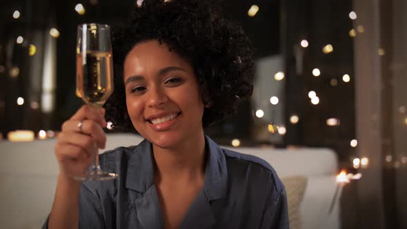 Happy Woman with Champagne and Sparkler at Night