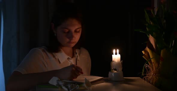 a girl writes poem at night by candlelight