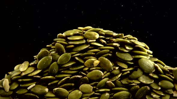 Pumpkin seeds are pouring on a black background.