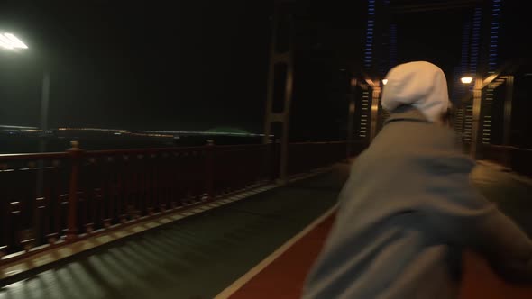 Modern Girl Dancing at Night on the Bridge Against the Background of a Big City