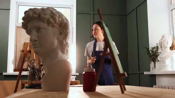 Art Studio  Happy Young Woman Drawing a Painting  Marble Bust Sculpture on the Foreground