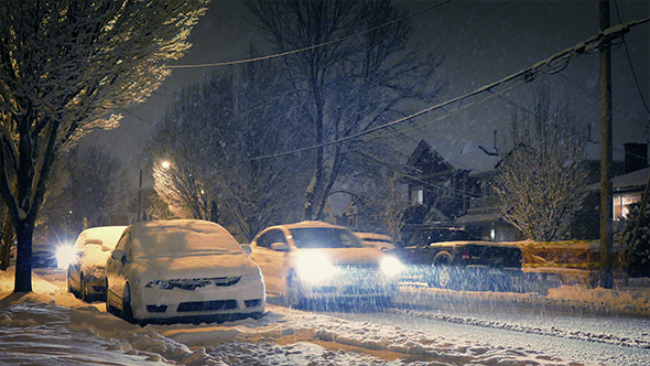 Cars Pass Houses At Night In Blizzard alt