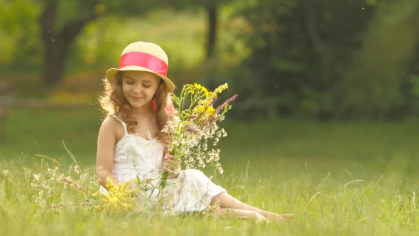 Child Holds a Bouquet of Wildflowers in Her Hands, She Smells Them and Smiles