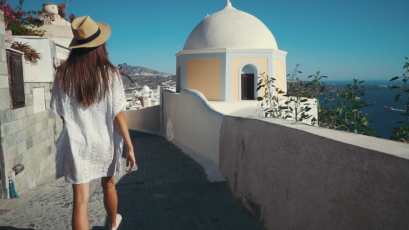 Young Sexy Woman Is on the Greek Island Santorini in a White Dress and and Straw Hat White Greek