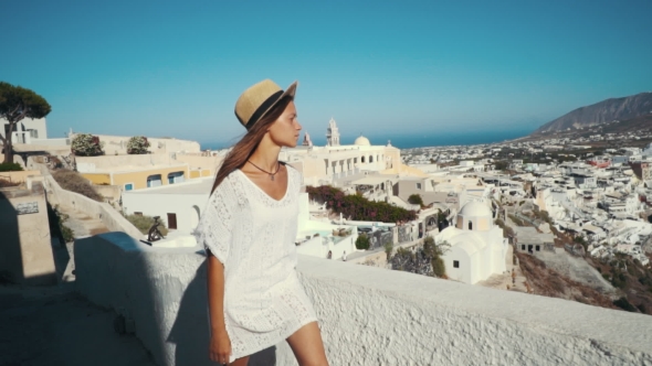 Young Sexy Woman Is on the Greek Island Santorini in a White Dress and and Straw Hat White Greek