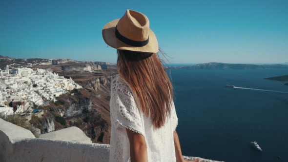 Young Sexy Woman Is on the Greek Island Santorini in a White Dress and and Straw Hat White Greek