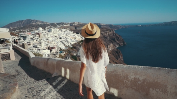 Young Sexy Woman Is on the Greek Island Santorini in a White Dress and and Straw Hat White Greek