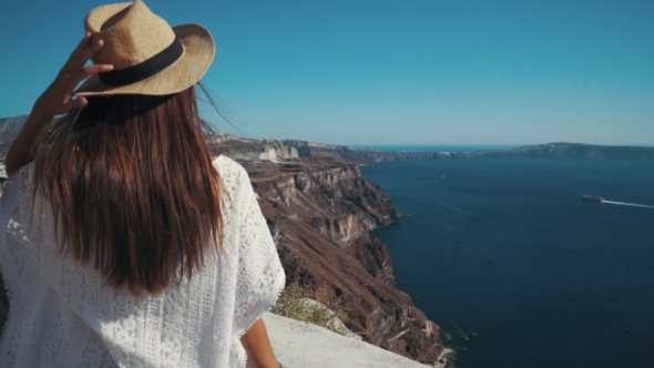 Young Sexy Woman Is on the Greek Island Santorini in a White Dress and and Straw Hat White Greek