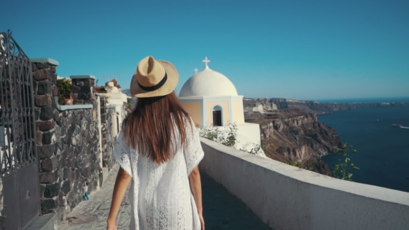 Young Sexy Woman Is on the Greek Island Santorini in a White Dress and and Straw Hat White Greek