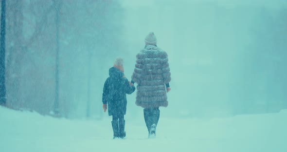 Woman with a Child Go in the Winter in Heavy Snow