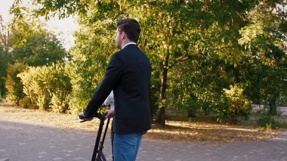 Two Handsome Young Businessman Riding an Electric Scooters on the Road in City Park Slow Motion