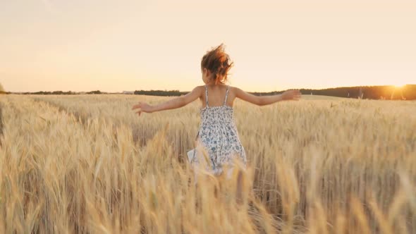 Happy Little Beautiful Girl Running Across the Field at Sunset