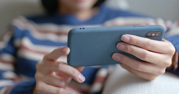 Woman watch on cellphone and sit on sofa at home