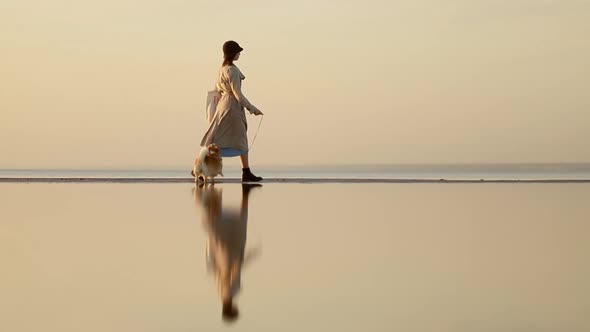 Woman and Dog Walk Along Beach on Autumn Evening While Traveling Outside Spbi