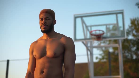 Closeup Slow Motion at Sunrise Muscular Guy with Dyed Hair and Naked Torso Looking at Camera Smiling