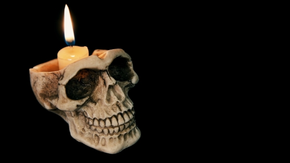 Skull with a Burning Candle on a Black Background