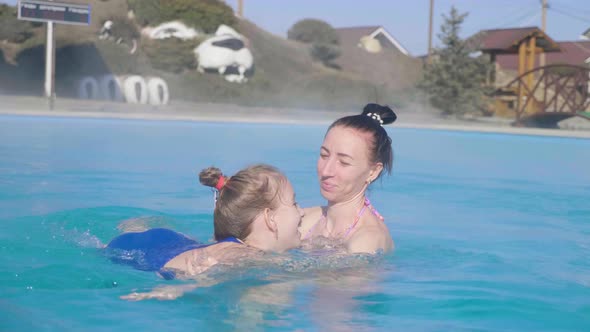 Happy Mother and Daughter Bathe Pool Border in a Natural Thermal SPA.