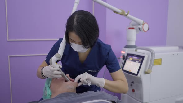 Asian Doctor Performs Aesthetic Treatment on Patient with Laser Device