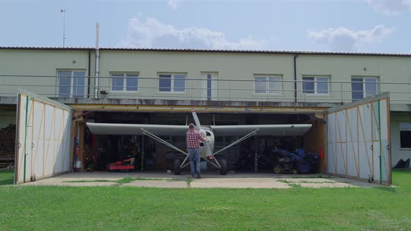 Aviator Fixing Airplane Propeller Inside Repair Hangar on Countryside Aerodrome