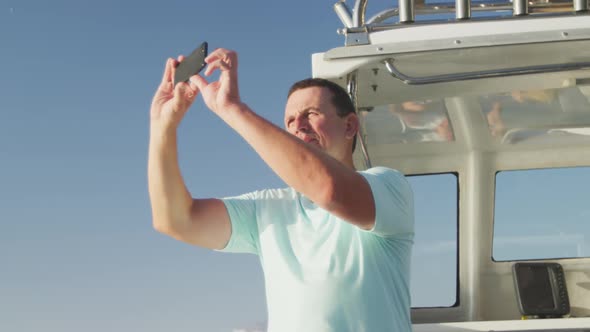 Side view of a Caucasian man on boat taking photos with his phone
