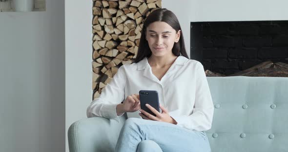 Young Woman Looking at Smartphone Screen Watching Funny Photo or Video