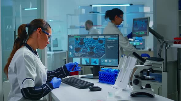 Chemist Doctor Holding Test Tube with Blood Sample Entering Datas in Pc