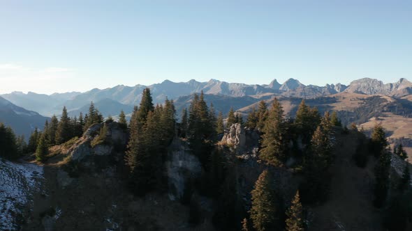 Aerial dolly of mountain top with trees with large mountains in the background