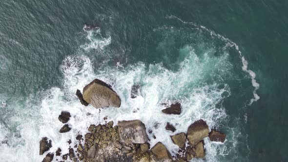 Top down aerial view of giant ocean waves crashing and foaming in coral beach