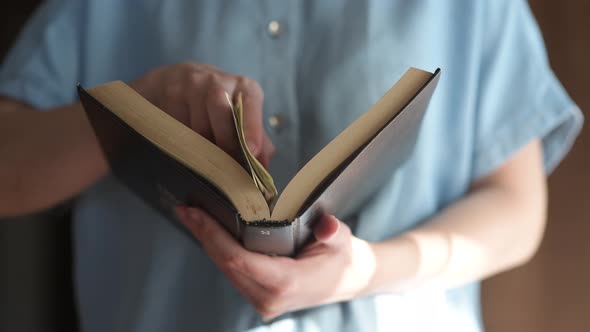 A girl opens a book and hides a few dollar bills there. Stock just in case