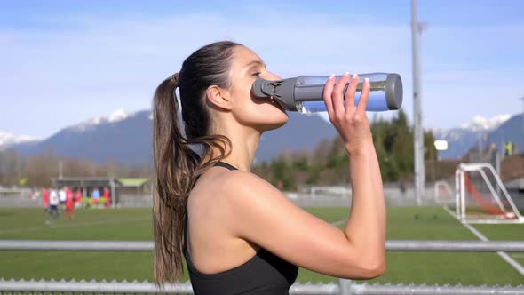 Attractive young athletic woman drinking water after run Slow motion