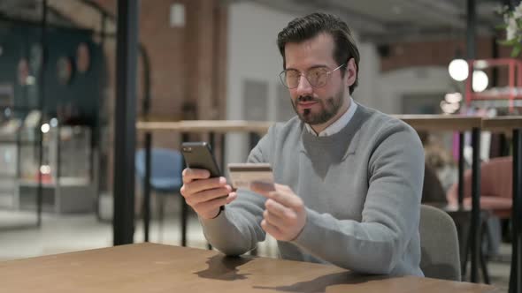 Young Man Making Online Payment on Smartphone