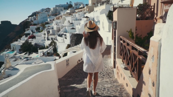 Young Sexy Woman Is on the Greek Island Santorini in a White Dress and and Straw Hat White Greek