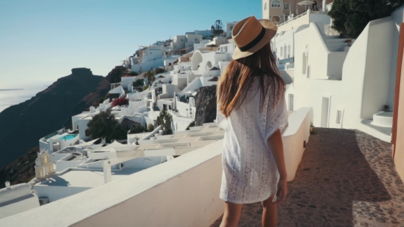 Young Sexy Woman Is on the Greek Island Santorini in a White Dress and and Straw Hat White Greek