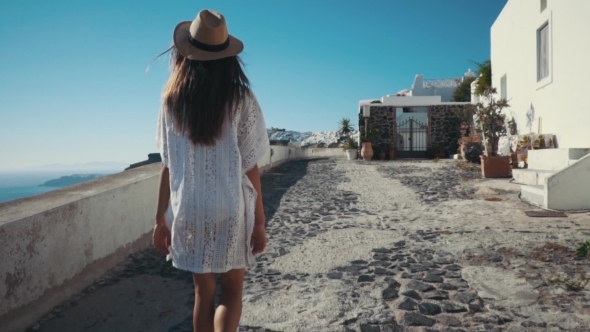 Young Sexy Woman Is on the Greek Island Santorini in a White Dress and and Straw Hat White Greek