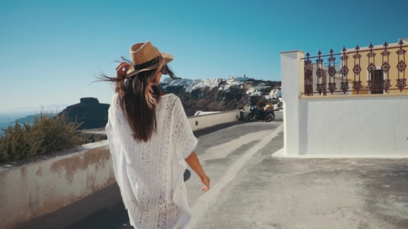 Young Sexy Woman Is on the Greek Island Santorini in a White Dress and and Straw Hat White Greek