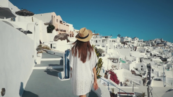 Young Sexy Woman Is on the Greek Island Santorini in a White Dress and and Straw Hat White Greek