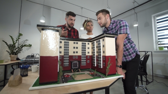 Co-workers Discussing By Miniature of Building