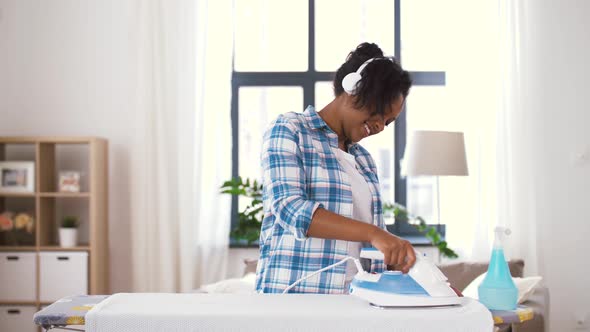 African American Woman Ironing Bed Linen at Home