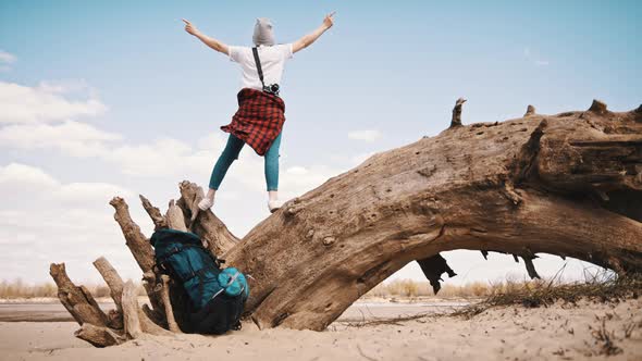 Happy Young Woman Standing on the Tree Trunk on the Sandy Beach with Outstretched Hands. Backpacker